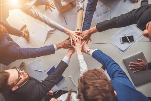 devops-mindset-teamwork Team mit Händen in der Mitte zur Darstellung von Devops als Mindset