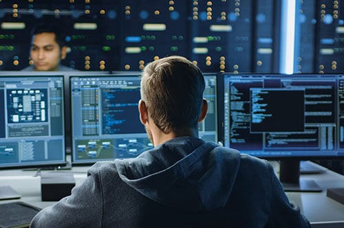 Software-Qualitaet Mann von hinten schaut auf 3 Bildschirme Software Qualität