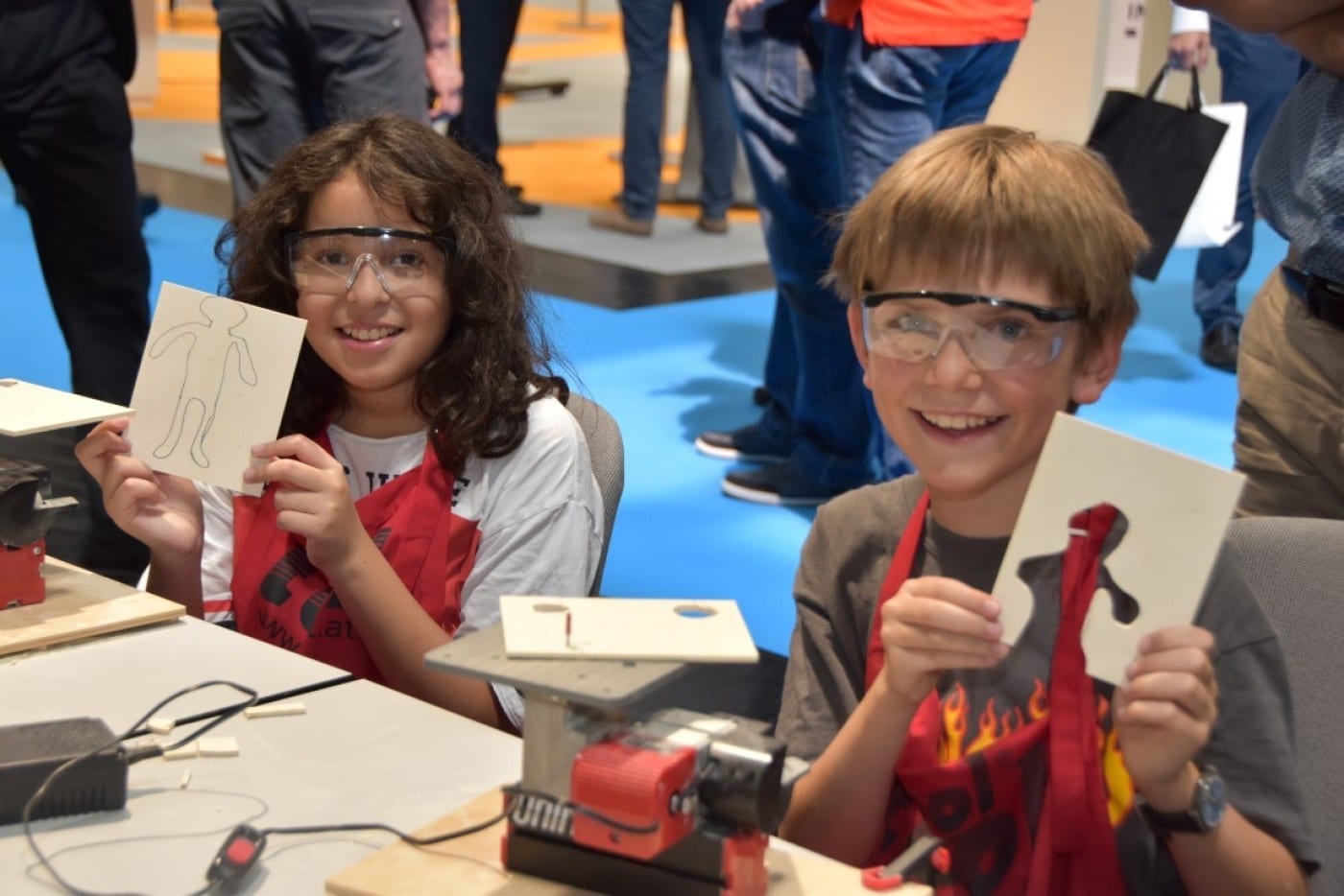 technik-weorkshop-junge-baut 2 Kinder halten Sägearbeit in die Kamera.